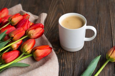 Taze turuncu laleler ve bahar kompozisyonlu kapuçino kupası. Sevgililer Günü, Kadınlar Günü ve Anneler Günü için fotokopi alanı olan tebrik kartı..