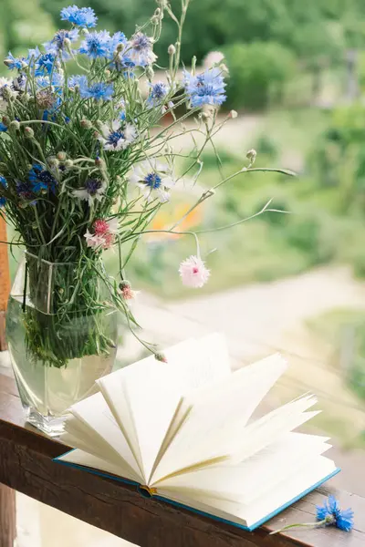 Pencere kenarında güzel bir yaz, sakin bir hayat. Bir buket çiçek ve rahat bir evin pencere eşiğinde bir kitap..