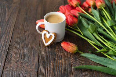Taze turuncu laleler ve bahar kompozisyonlu kapuçino kupası. Sevgililer Günü, Kadınlar Günü ve Anneler Günü için fotokopi alanı olan tebrik kartı..
