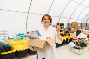 Gönüllü kadın insanlar için bağış kutuları hazırlıyor. Mülteciler için bağış giysileri, savaş mağdurlarına destek. İnsani yardım kavramı. İnsanlara yardım etmek.