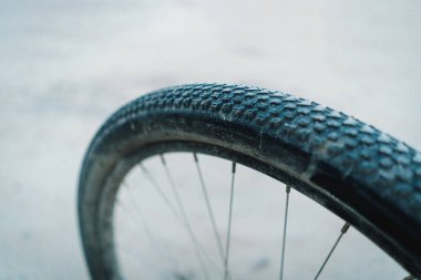 Bu görüntü, dağ bisikletlerinin arka tekerlekleri ve kasetlerinin yakın çekimini gösteriyor. Tekerlek çamurla kaplı ve kaset çok yıpranmış. Görüntü alçaktan çekiliyor, direksiyona bakıyor..