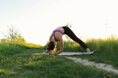 Güneşli bir yaz günbatımında spor ya da yoga yapan güzel bir kız. Vücut pozitifliği, kadınlar için spor, uyum, sağlıklı yaşam tarzı, kendini sevme ve refah..