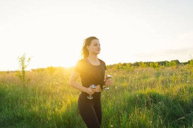 Güneşli bir yaz günbatımında spor ya da yoga yapan güzel bir kız. Vücut pozitifliği, kadınlar için spor, uyum, sağlıklı yaşam tarzı, kendini sevme ve refah..