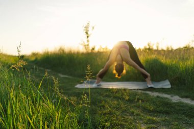 Güneşli bir yaz günbatımında spor ya da yoga yapan güzel bir kız. Vücut pozitifliği, kadınlar için spor, uyum, sağlıklı yaşam tarzı, kendini sevme ve refah..