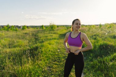 Güneşli bir yaz günbatımında spor ya da yoga yapan güzel bir kız. Vücut pozitifliği, kadınlar için spor, uyum, sağlıklı yaşam tarzı, kendini sevme ve refah..