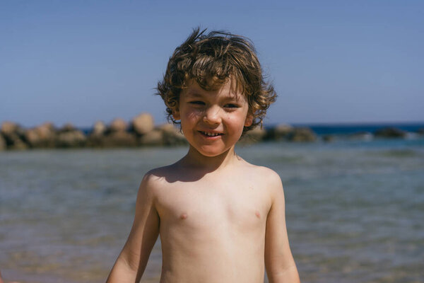 Young Boy Curly Brown Hair Smiles Camera Stands Beach Ocean Royalty Free Stock Images