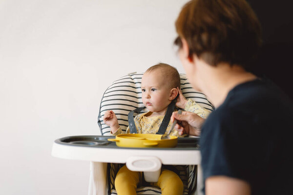 Baby Girl Sits High Chair Being Fed Mother Baby Wearing Stock Image