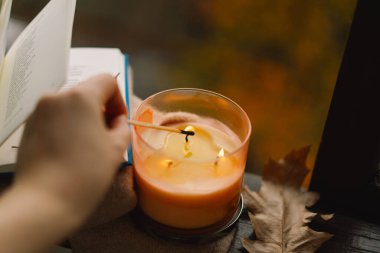 Yanan kibritle birlikte, pencere eşiğinde mum yakarak, sıcak sonbaharda süveter, mum ve sonbahar dekoruyla, sakin bir hayat süreceğim. Sonbahar evi dekorasyonu. Sıcak sonbahar havası.