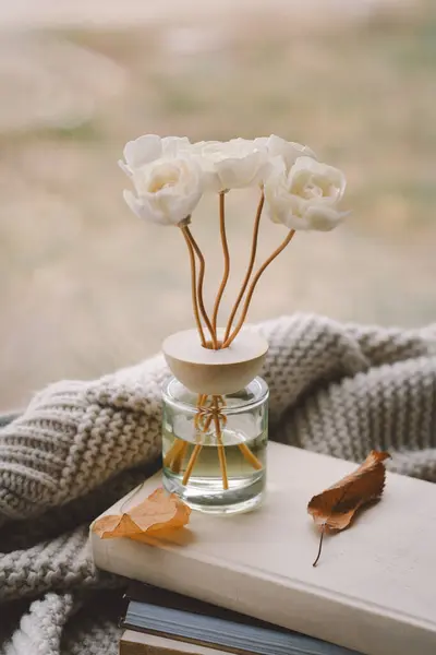 stock image Cozy indoor setting with a Incense sticks for the home with a floral scent surrounded by a cozy knitted blanket and scattered leaves, creating a serene atmosphere in a relaxed indoor space.