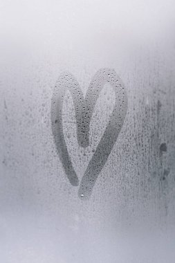 Heart shape drawn on a foggy window, capturing a moment of warmth and intimacy in a cool environment clipart