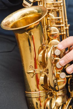 Bir saksafoncu, sonbaharda yapraklarla çevrili bir bankta otururken sakin bir parkta gösteri yapar.