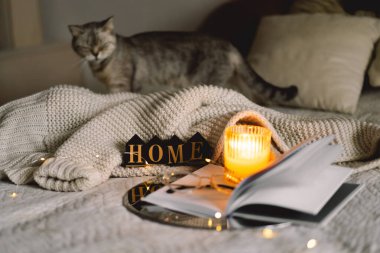 Açık bir kitapla kokulu mum, kalp şeklinde katlanmış çarşaflar sıcak bir battaniyeyle yatakta. Kış tatili. Eviniz güzelmiş. Konforlu ev