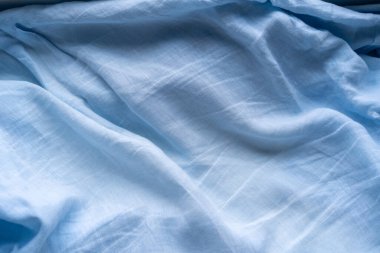 Açık mavi kumaş bir yüzey boyunca yumuşak bir şekilde uzanır, sükuneti çağrıştıran nazik dalgalar yaratır. Pürüzsüz doku ve renk, huzurlu ortamı güçlendirir, rahat anlar için idealdir..