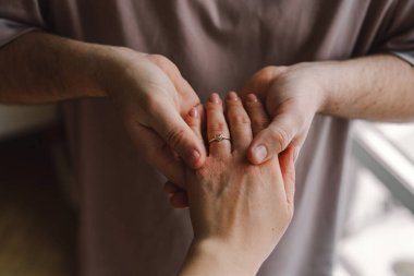 Bir çift, bir partnerin diğer parmağına nişan yüzüğü takmasıyla özel bir anı paylaşıyor. Romantik bir jest. Sevgililer Günün kutlu olsun..