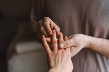 Bir çift, bir partnerin diğer parmağına nişan yüzüğü takmasıyla özel bir anı paylaşıyor. Romantik bir jest. Sevgililer Günün kutlu olsun..