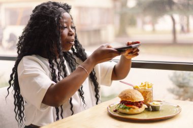 Kafede telefon kullanan Afrikalı bir kadın. Teknoloji kullanan insanlar
