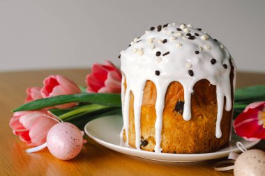 Güzel dekore edilmiş paskalya pastası üzerine krema serpiştirilmiş ve çikolata parçacıkları çikolata tavşanı ve pastel yumurtaların yanında duruyor. Neşeli düzenleme bayram neşesi yayıyor.