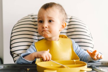 Sağlam beslenmiş küçük bir çocuk. Küçük kız parmak yiyor ve sebze tabağını karıştırıyor..