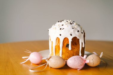 Güzel dekore edilmiş paskalya pastası üzerine krema serpiştirilmiş ve çikolata parçacıkları çikolata tavşanı ve pastel yumurtaların yanında duruyor. Neşeli düzenleme bayram neşesi yayıyor.