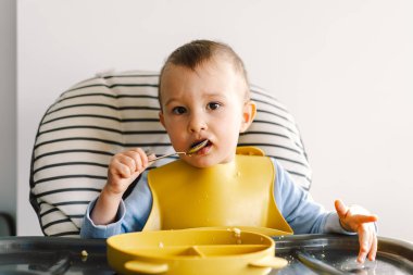 Sağlam beslenmiş küçük bir çocuk. Küçük kız parmak yiyor ve sebze tabağını karıştırıyor..