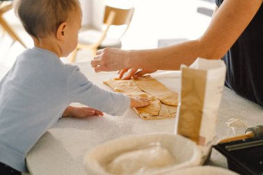 Mutlu aile birlikte fırın hazırlıyor. Anne ve kız çocuk kurabiye pişiriyor ve mutfakta eğleniyorlar. Ev yapımı yemek ve küçük bir yardımcı.