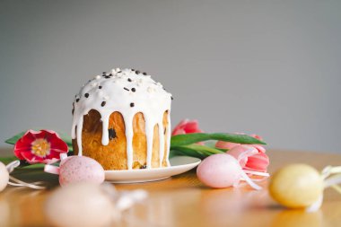 Güzel dekore edilmiş paskalya pastası üzerine krema serpiştirilmiş ve çikolata parçacıkları çikolata tavşanı ve pastel yumurtaların yanında duruyor. Neşeli düzenleme bayram neşesi yayıyor.