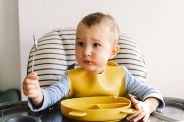 Sağlam beslenmiş küçük bir çocuk. Küçük kız parmak yiyor ve sebze tabağını karıştırıyor..