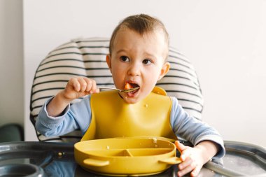 Sağlam beslenmiş küçük bir çocuk. Küçük kız parmak yiyor ve sebze tabağını karıştırıyor..