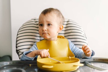 Sağlam beslenmiş küçük bir çocuk. Küçük kız parmak yiyor ve sebze tabağını karıştırıyor..