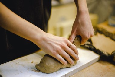 Çömlek atölyesinde kilden bir tencereyi ustalıkla şekillendiren eller. Atölye yaratıcılığı teşvik ediyor ve yeni başlayanlara rahat bir ortamda çömlek teknikleri öğretmeye odaklanıyor..