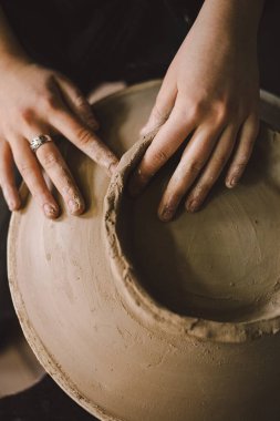 Çömlek atölyesinde kilden bir tencereyi ustalıkla şekillendiren eller. Atölye yaratıcılığı teşvik ediyor ve yeni başlayanlara rahat bir ortamda çömlek teknikleri öğretmeye odaklanıyor..