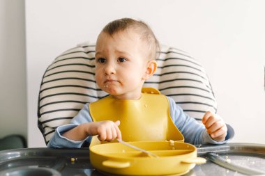 Sağlam beslenmiş küçük bir çocuk. Küçük kız parmak yiyor ve sebze tabağını karıştırıyor..