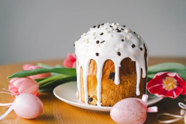 Güzel dekore edilmiş paskalya pastası üzerine krema serpiştirilmiş ve çikolata parçacıkları çikolata tavşanı ve pastel yumurtaların yanında duruyor. Neşeli düzenleme bayram neşesi yayıyor.