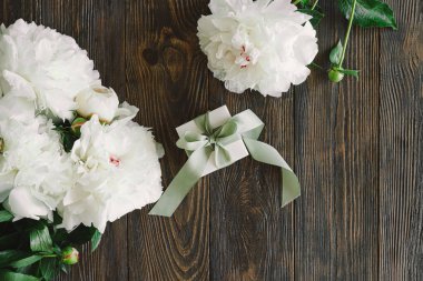 Ahşap arka planda hediye kutuları olan bir buket güzel beyaz şakayık. Şık bir çiçek selamı. Anneler Günü