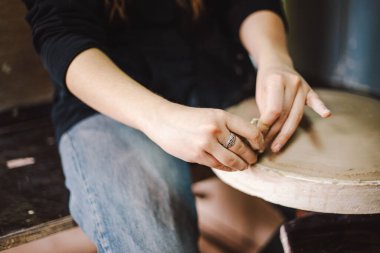 Çömlek atölyesinde kilden bir tencereyi ustalıkla şekillendiren eller. Atölye yaratıcılığı teşvik ediyor ve yeni başlayanlara rahat bir ortamda çömlek teknikleri öğretmeye odaklanıyor..