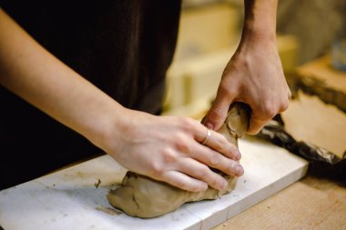 Çömlek atölyesinde kilden bir tencereyi ustalıkla şekillendiren eller. Atölye yaratıcılığı teşvik ediyor ve yeni başlayanlara rahat bir ortamda çömlek teknikleri öğretmeye odaklanıyor..