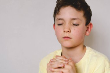 Elleri bağlı bir çocuk, dua ediyor ya da meditasyon yapıyor. Hıristiyanlık, din ve inanç kavramı.