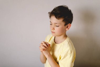 Elleri bağlı bir çocuk, dua ediyor ya da meditasyon yapıyor. Hıristiyanlık, din ve inanç kavramı.