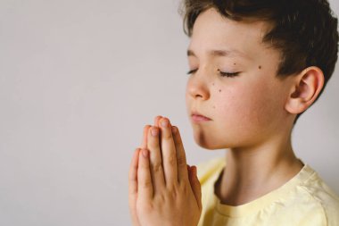 Elleri bağlı bir çocuk, dua ediyor ya da meditasyon yapıyor. Hıristiyanlık, din ve inanç kavramı.