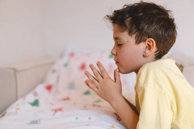 Elleri bağlı bir çocuk, dua ediyor ya da meditasyon yapıyor. Hıristiyanlık, din ve inanç kavramı.