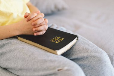 Bir çocuk kutsal kitabı okuyor ve dua ediyor ya da meditasyon yapıyor. Hıristiyanlık, din ve inanç kavramı.