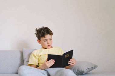 Bir çocuk kutsal kitabı okuyor ve dua ediyor ya da meditasyon yapıyor. Hıristiyanlık, din ve inanç kavramı.