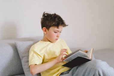 Bir çocuk kutsal kitabı okuyor ve dua ediyor ya da meditasyon yapıyor. Hıristiyanlık, din ve inanç kavramı.