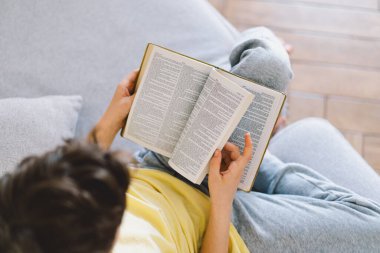 Bir çocuk kutsal kitabı okuyor ve dua ediyor ya da meditasyon yapıyor. Hıristiyanlık, din ve inanç kavramı.
