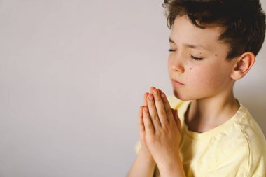 Elleri bağlı bir çocuk, dua ediyor ya da meditasyon yapıyor. Hıristiyanlık, din ve inanç kavramı.