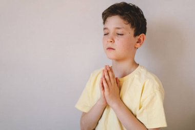 Elleri bağlı bir çocuk, dua ediyor ya da meditasyon yapıyor. Hıristiyanlık, din ve inanç kavramı.