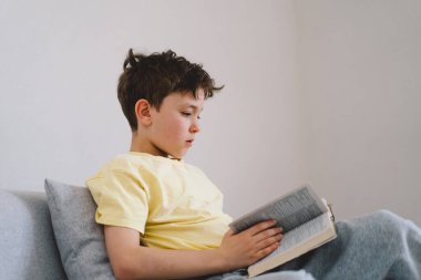 Bir çocuk kutsal kitabı okuyor ve dua ediyor ya da meditasyon yapıyor. Hıristiyanlık, din ve inanç kavramı.