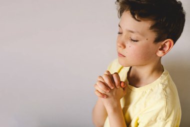 Elleri bağlı bir çocuk, dua ediyor ya da meditasyon yapıyor. Hıristiyanlık, din ve inanç kavramı.