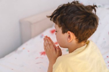 Elleri bağlı bir çocuk, dua ediyor ya da meditasyon yapıyor. Hıristiyanlık, din ve inanç kavramı.