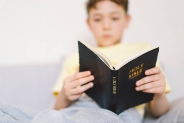 Bir çocuk kutsal kitabı okuyor ve dua ediyor ya da meditasyon yapıyor. Hıristiyanlık, din ve inanç kavramı.
